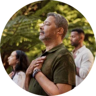 A man breathing deeply outdoors, hand on heart