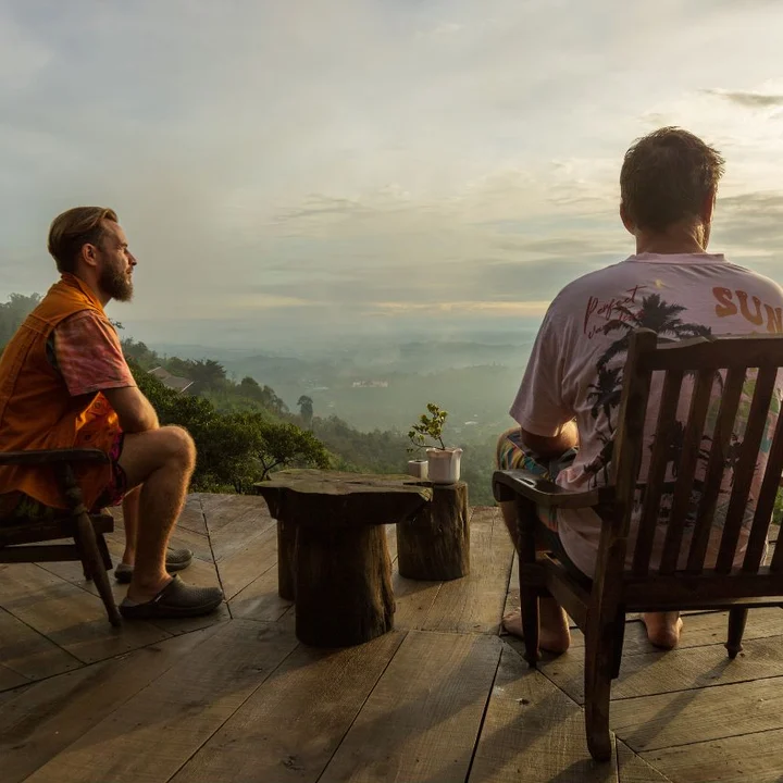 Two men on a deck looking out over the mountains at sunrise